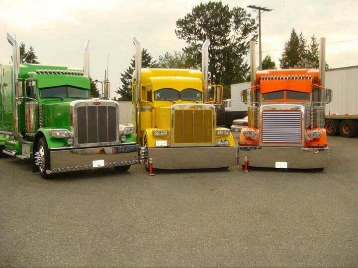 Three semi trucks parked in a row on the street.