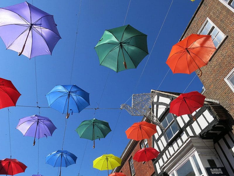 A bunch of umbrellas hanging from wires in the sky