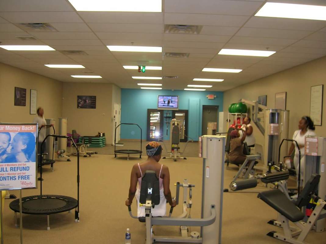 A woman is standing in the gym with other people.